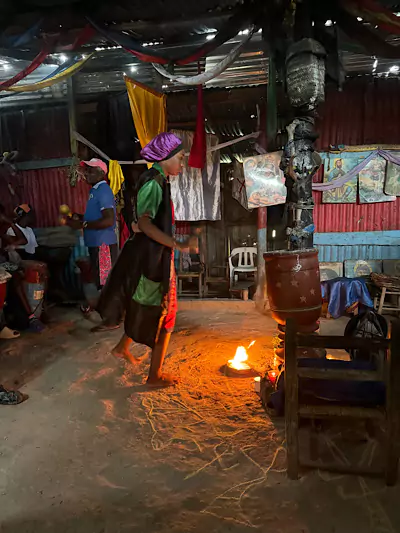 Frau in einer Hütte vor offenem Feuer