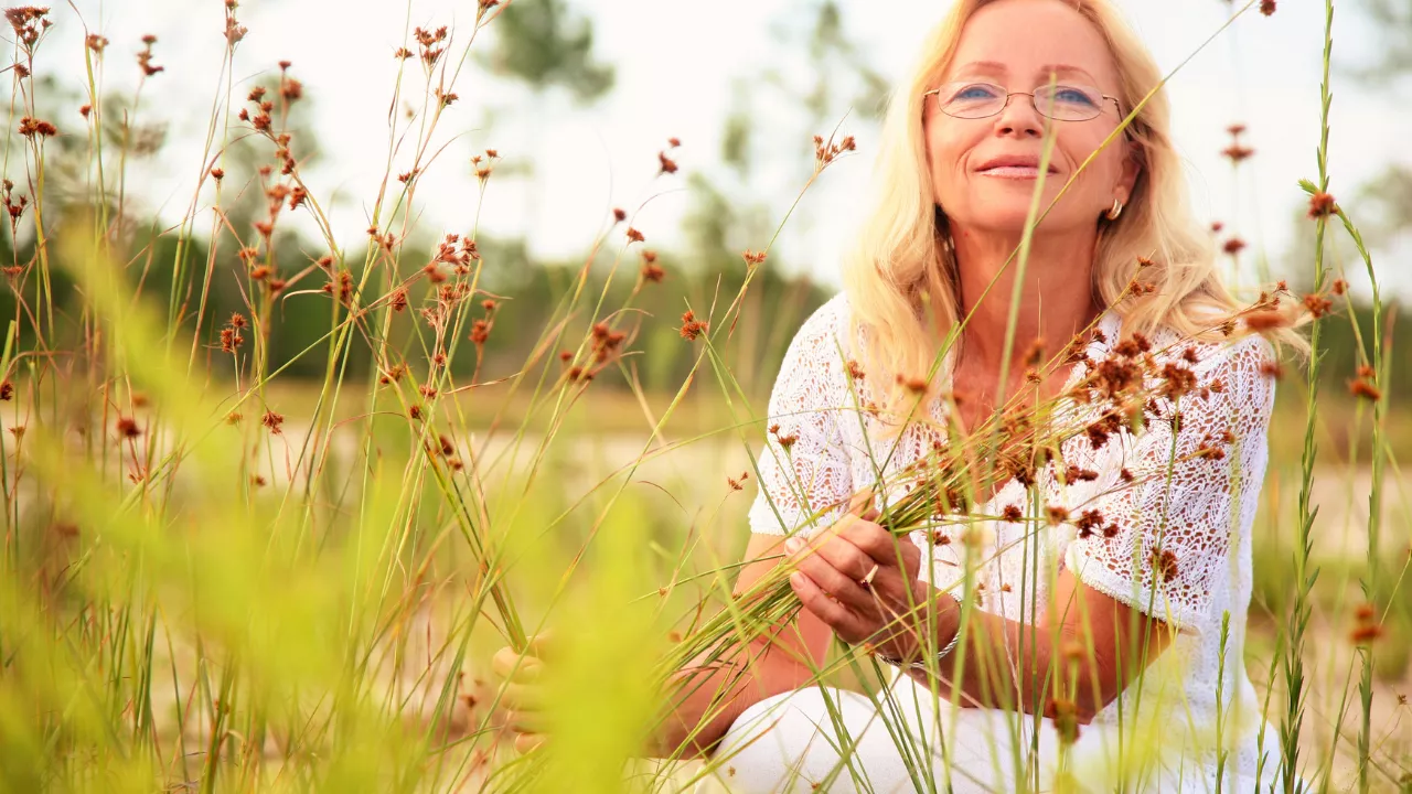 blonde Frau sitzt entspannt mit Blumen im Emotionale Sicherheit als Basis, um emotionales Essen zu überwinden